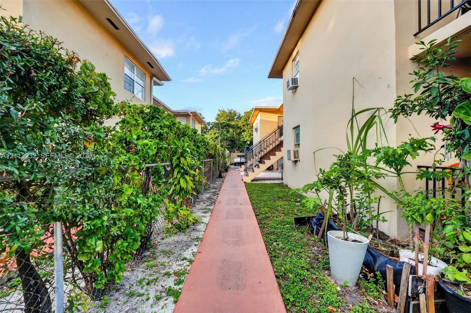 Exterior walkway featuring a paved pathway, stucco building facades, and integrated metal staircases