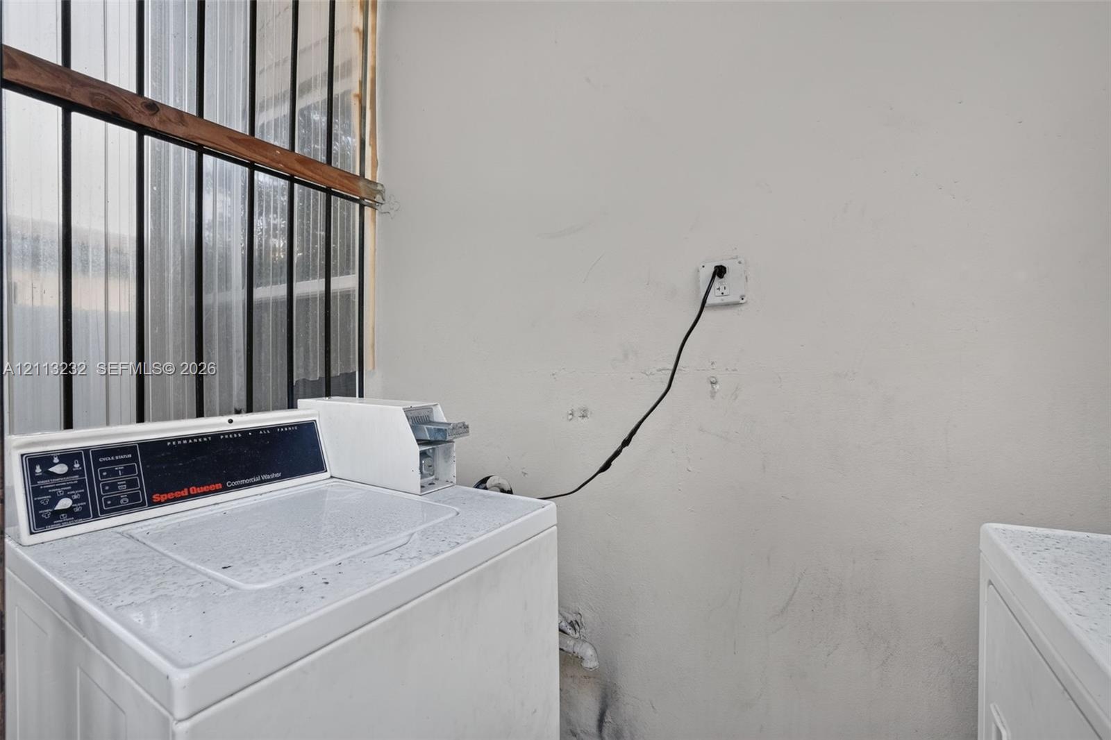 Utility area featuring metal security bars over the window and an electrical outlet