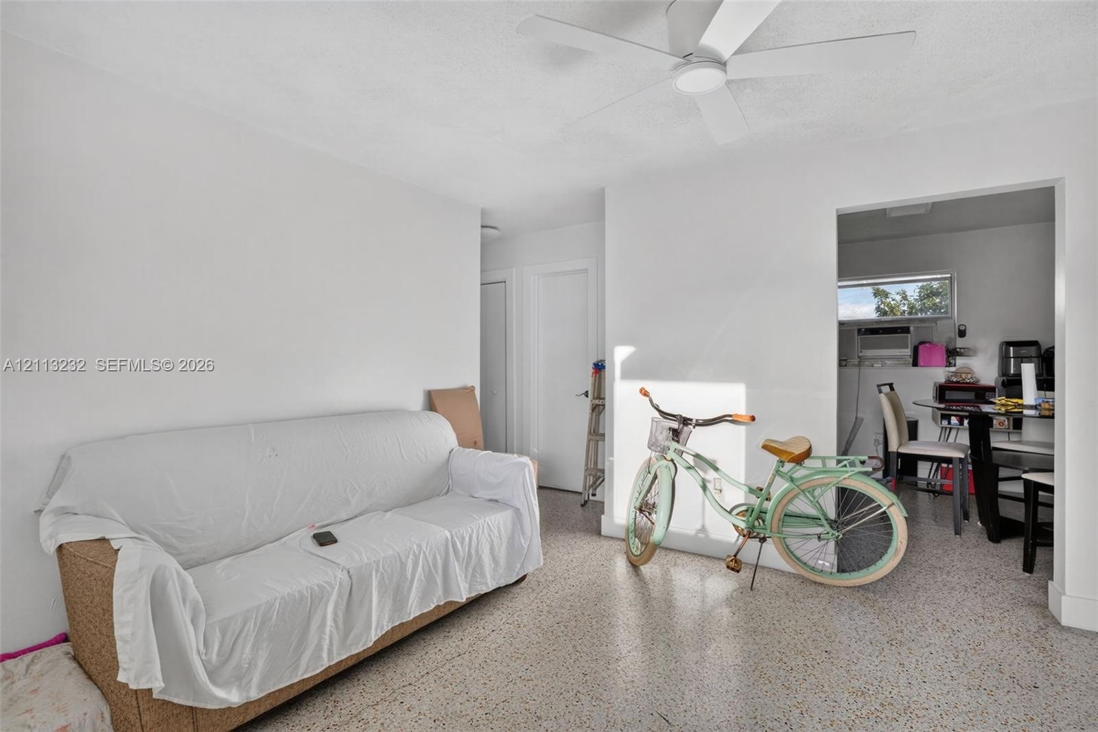 Interior space featuring speckled terrazzo flooring, white walls, and a ceiling-mounted fan with integrated lighting