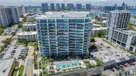 High-rise residential building featuring floor-to-ceiling glass paneling, a multi-level concrete facade, and an elevated outdoor swimming pool with ma