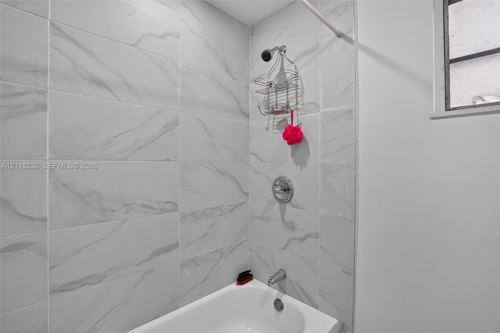 Full-height shower enclosure featuring large-format stone-patterned wall tile, chrome plumbing fixtures, and a white soaking tub