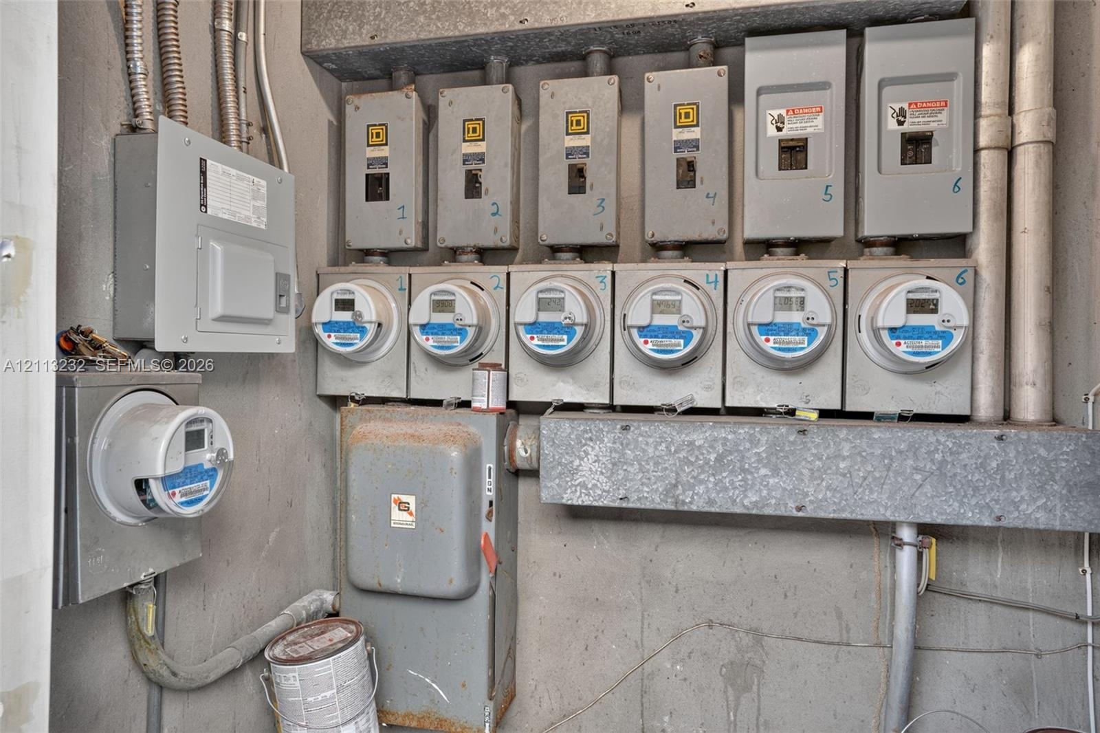 Bank of six individual electrical meters paired with corresponding circuit breaker disconnects and a separate primary service panel