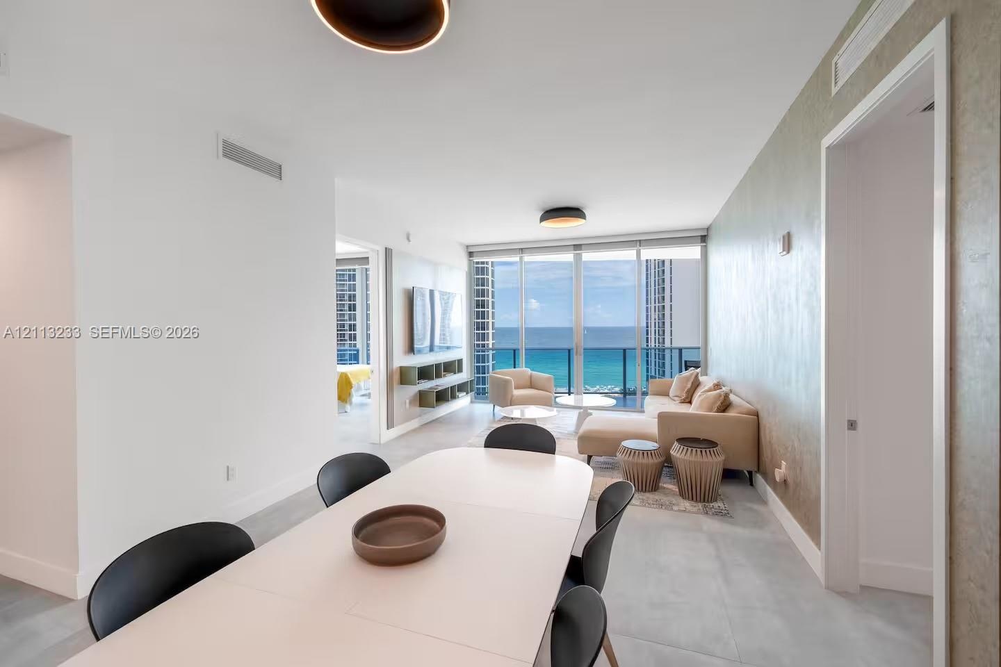 Open-concept interior featuring floor-to-ceiling glass, wall-mounted cabinetry, textured accent wall, and porcelain tile flooring