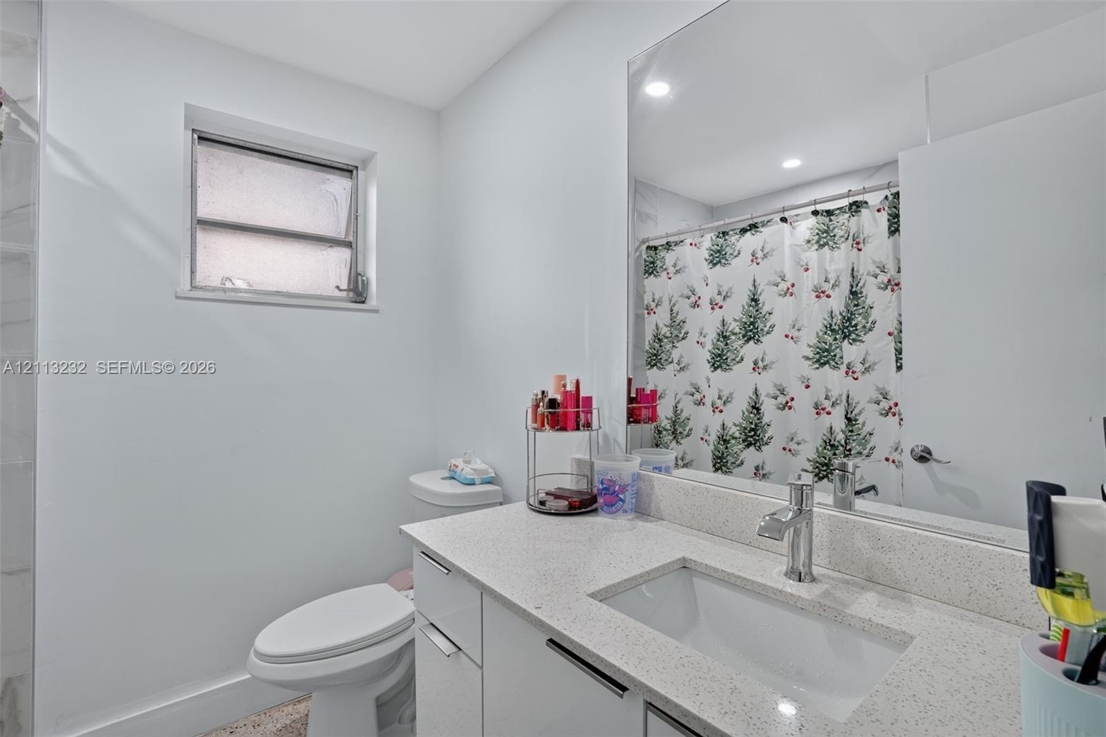 Bathroom featuring a vanity with a light-toned speckled countertop, an undermount rectangular sink, a chrome faucet, and a large-format vanity mirror 