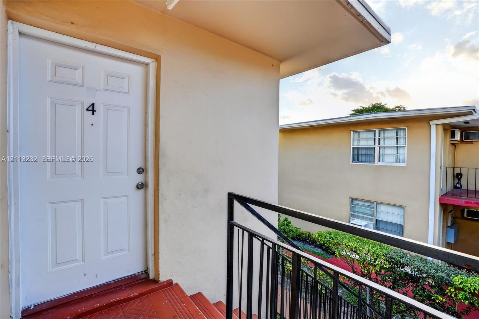 Exterior entry featuring a painted panel door, metal railing, and staircase