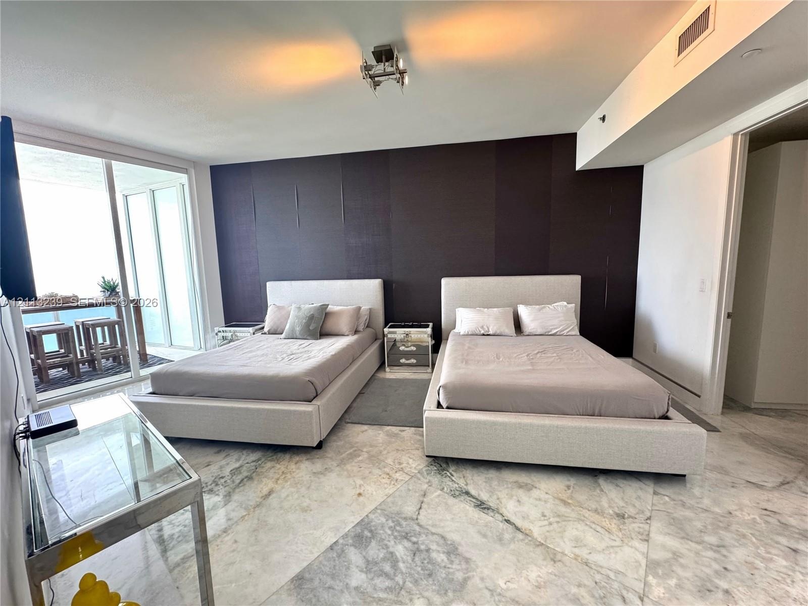 Large-format stone tile flooring, accent wall, and sliding glass balcony doors