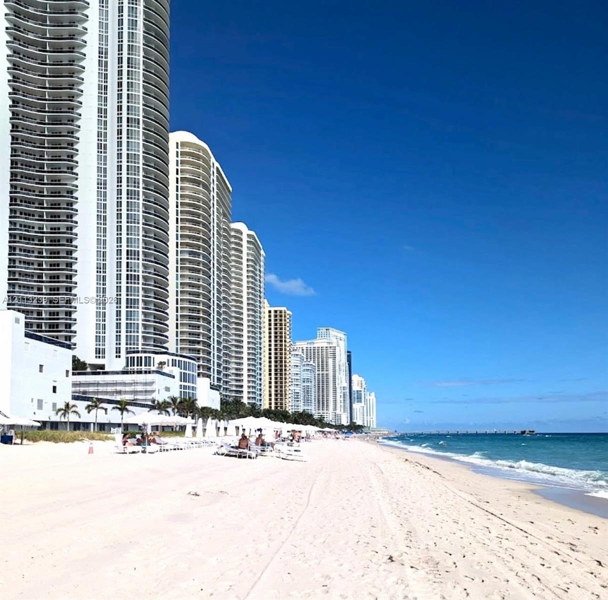 High-rise coastal architecture featuring stacked wrap-around balconies, situated along a private beachfront with direct ocean access