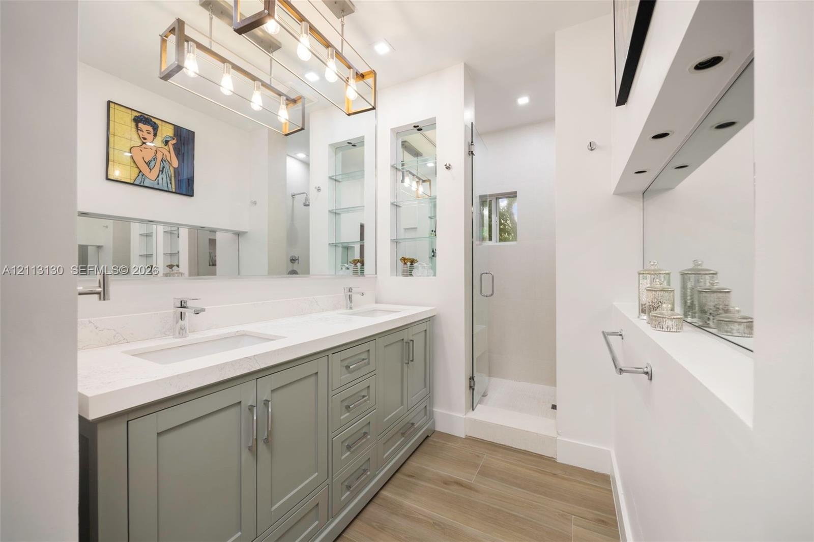 Dual-sink vanity with light gray shaker-style cabinetry, white solid-surface countertop, rectangular undermount sinks, and polished chrome fixtures, c