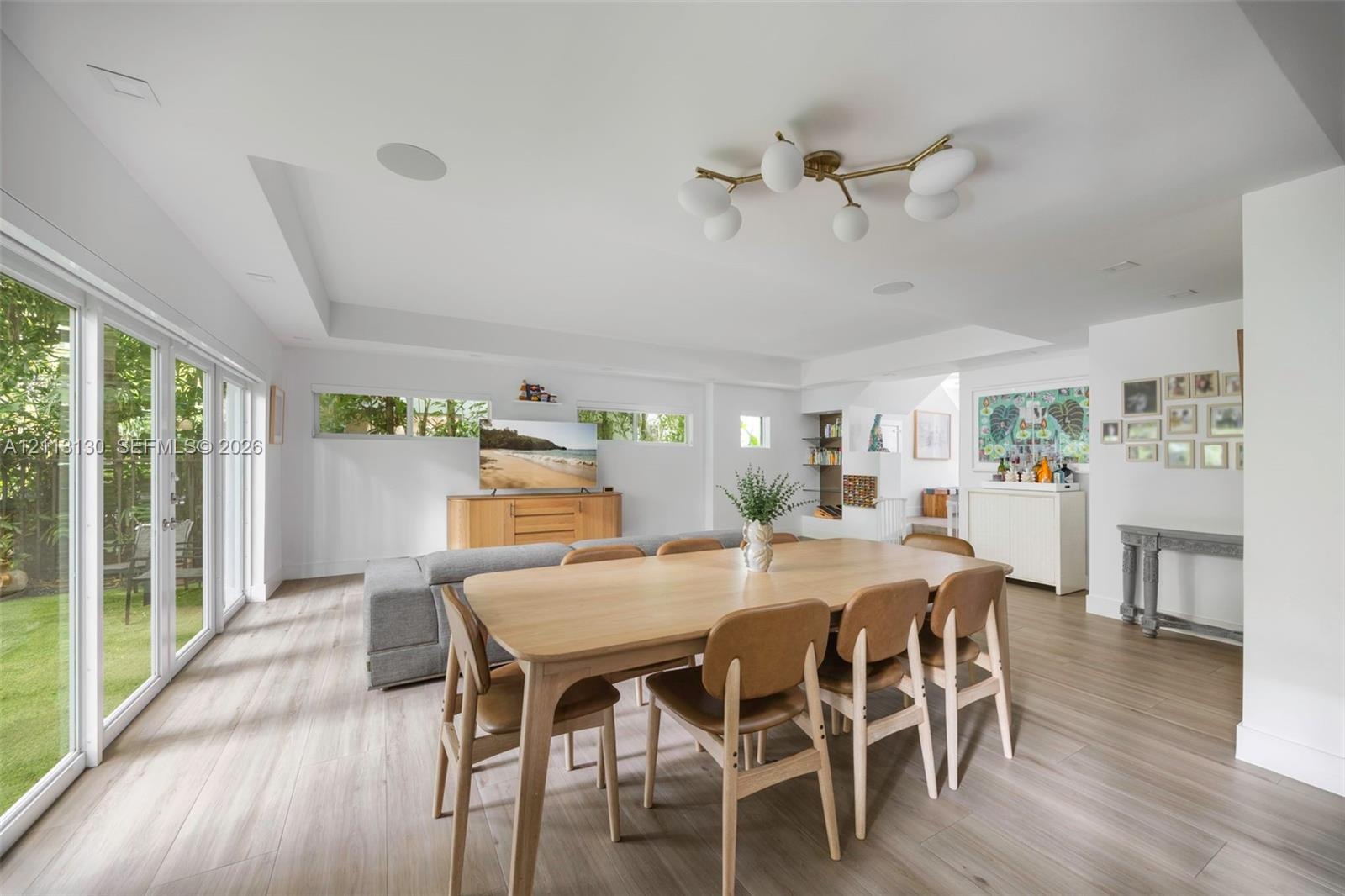 Open-concept living space featuring wood-finish flooring, multi-panel glass sliding doors, recessed ceiling lighting, clerestory windows, and a multi-