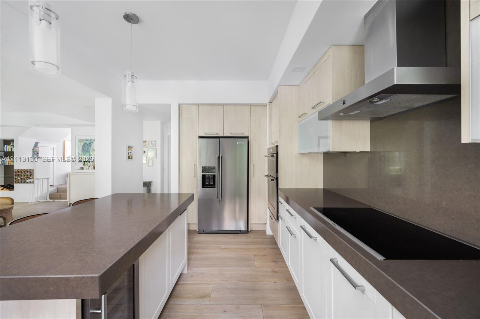Kitchen featuring wood-finish flooring, solid-surface countertops, stainless steel appliances, a built-in double oven, and pendant lighting