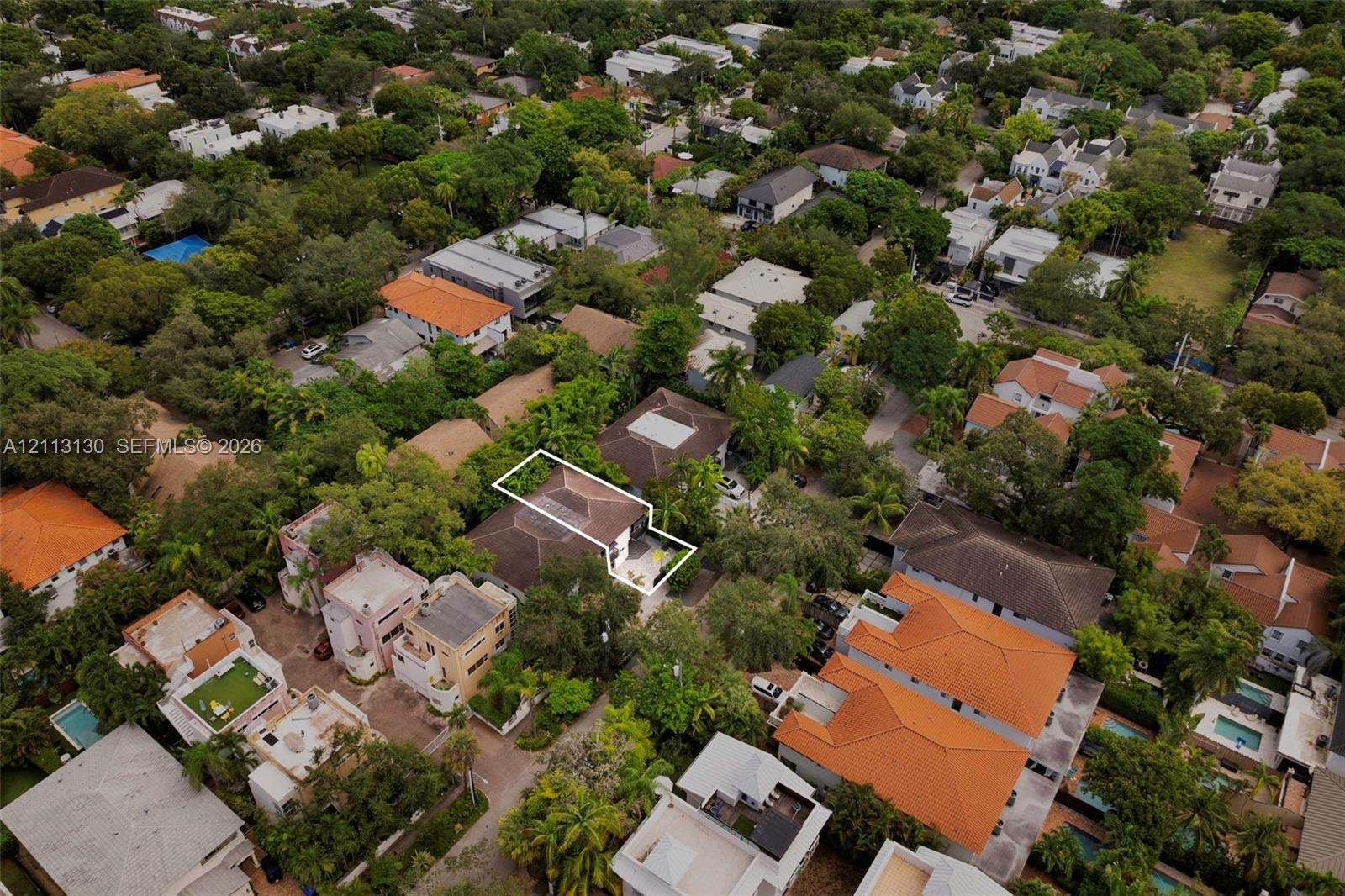 Aerial perspective showcasing a residential property with a hip roof, integrated hardscaping, and surrounding mature tree canopy