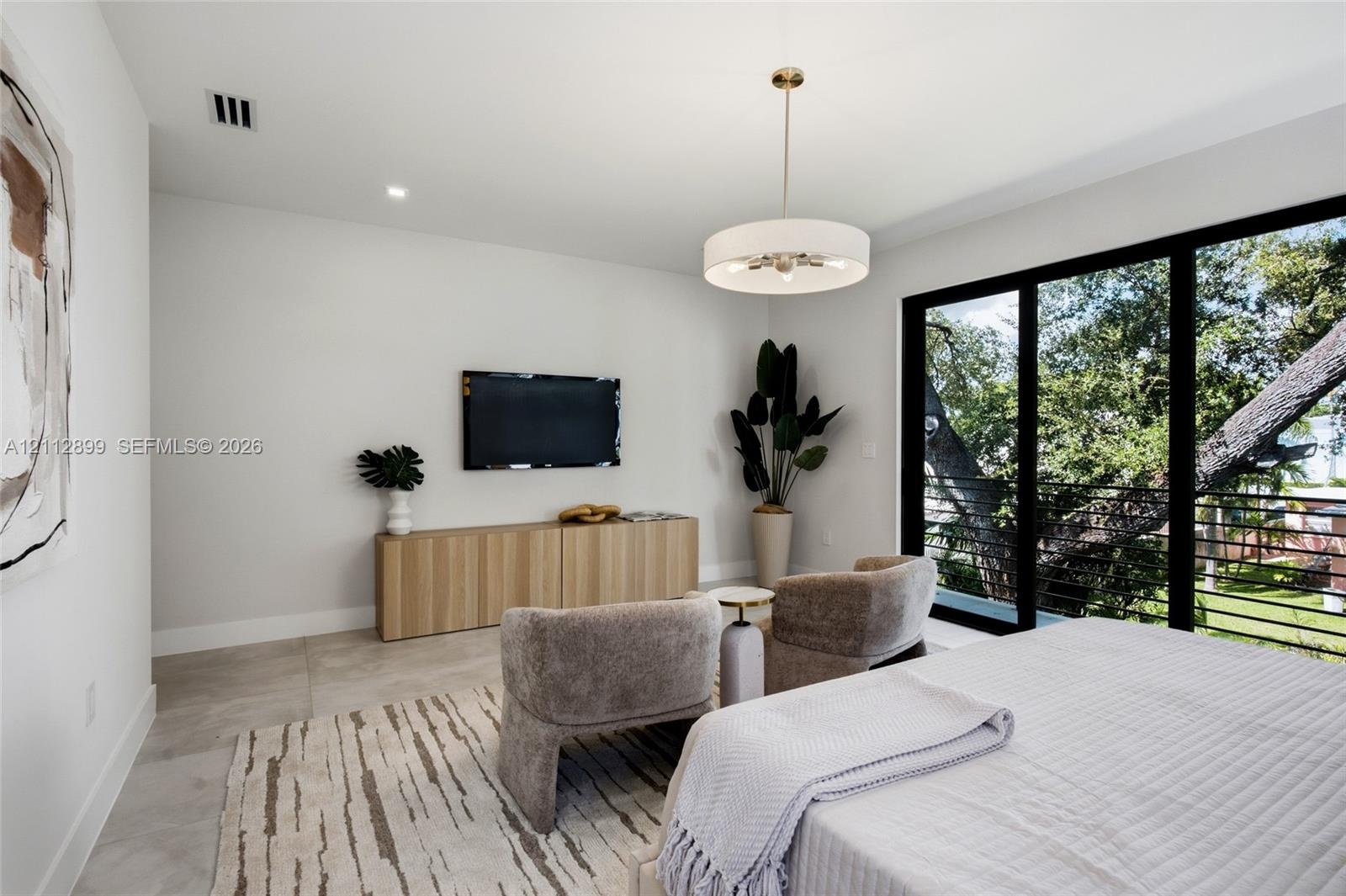 Large-format tile flooring, drum-style chandelier with metallic accents, built-in light-tone wood-finish cabinetry, and floor-to-ceiling sliding glass