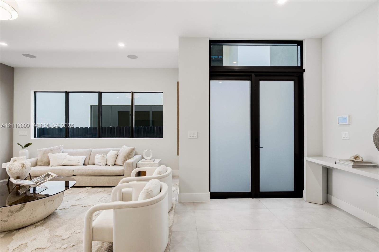 Double entry doors with frosted glass panels and an overhead transom window, large-format tile flooring, recessed lighting, and a built-in wall-mounte