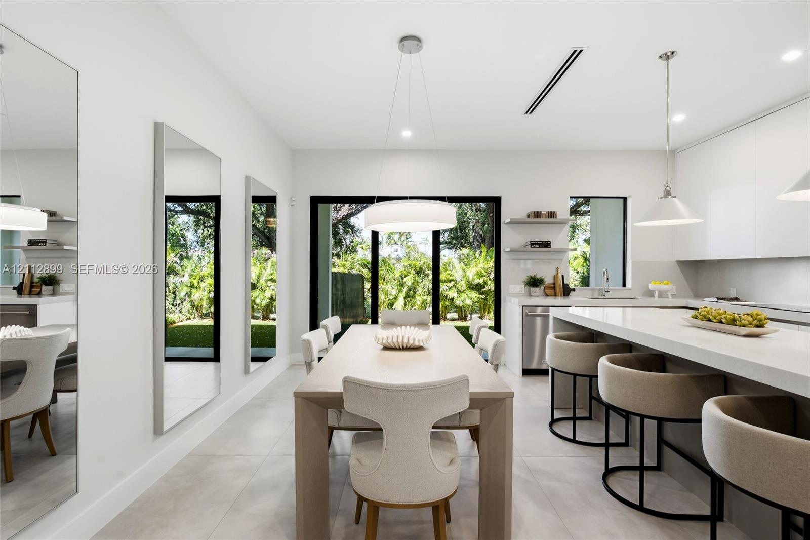 Modern kitchen featuring flat-panel cabinetry, a quartz waterfall island, large-format tile flooring, integrated linear lighting, and floor-to-ceiling
