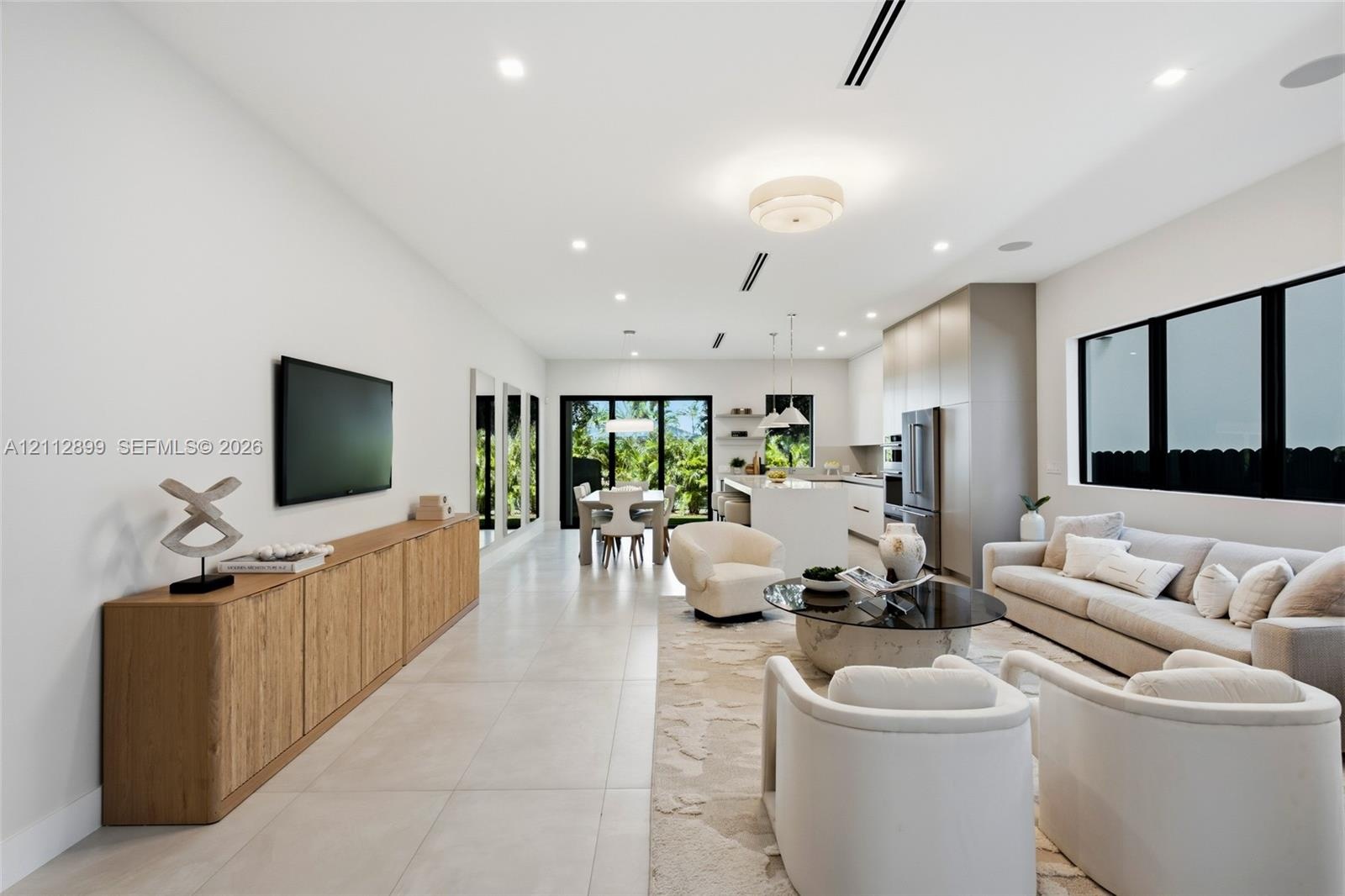 Open-concept living space featuring large-format tile flooring, recessed lighting, expansive glass sliding doors, built-in cabinetry, and a kitchen is