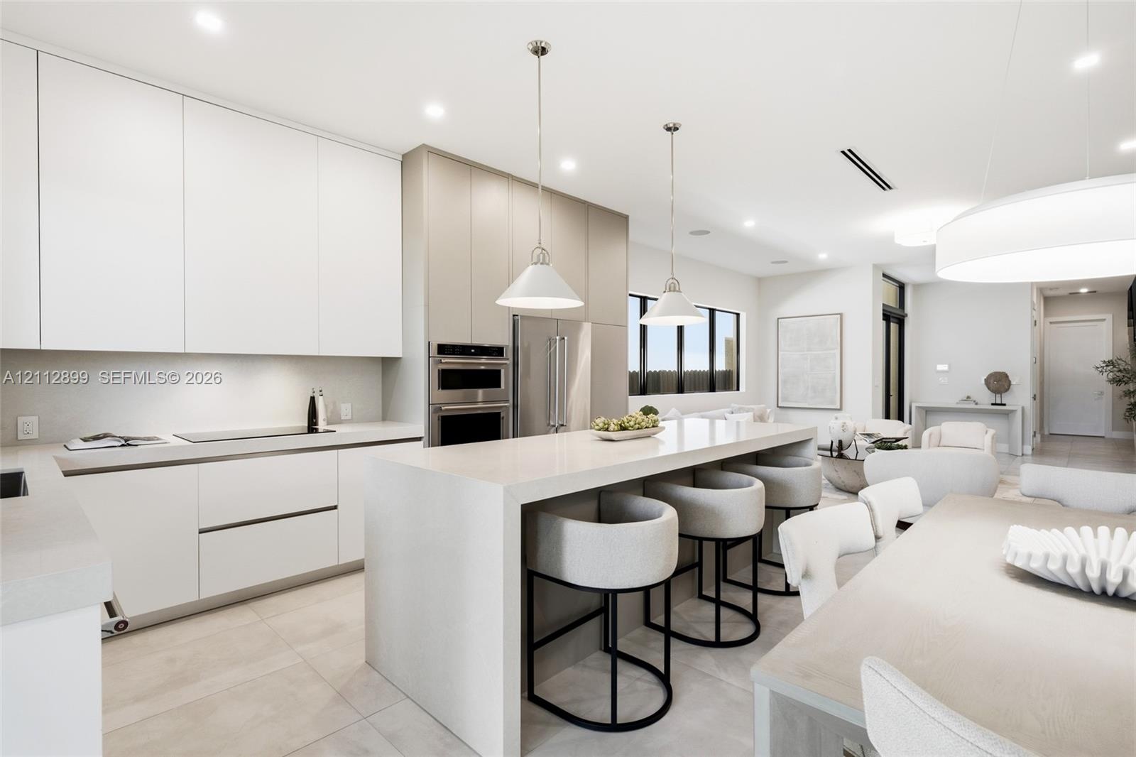 Kitchen featuring floor-to-ceiling cabinetry, a waterfall-edge center island, stone countertops, recessed lighting, and stainless steel built-in doubl