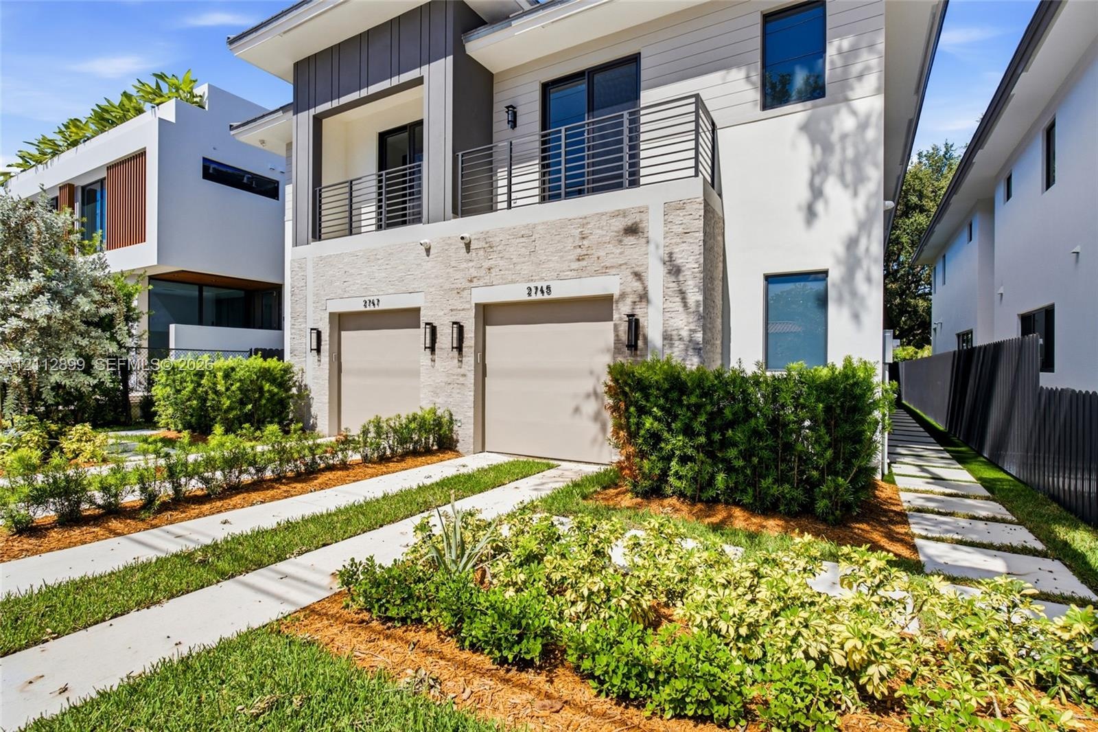 Modern two-story architectural exterior featuring smooth stucco, horizontal lap siding, and natural stone veneer accents