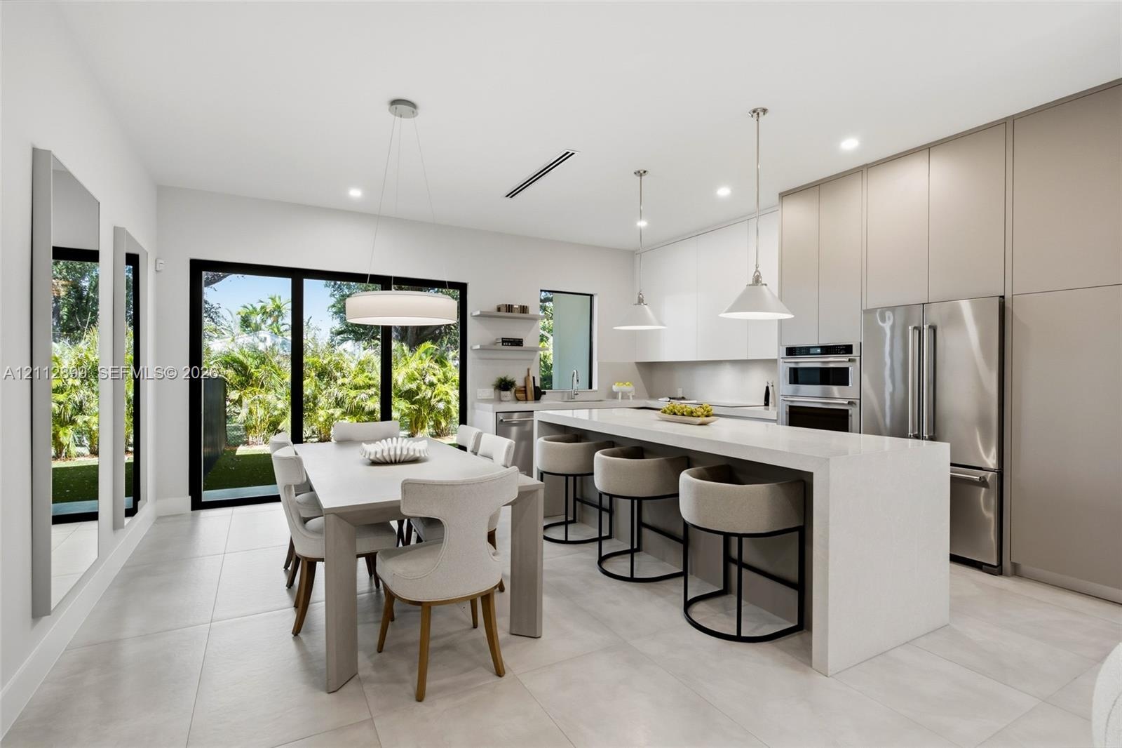 Kitchen featuring a waterfall-edge island with solid-surface countertops, floor-to-ceiling flat-panel cabinetry, stainless steel built-in appliances, 