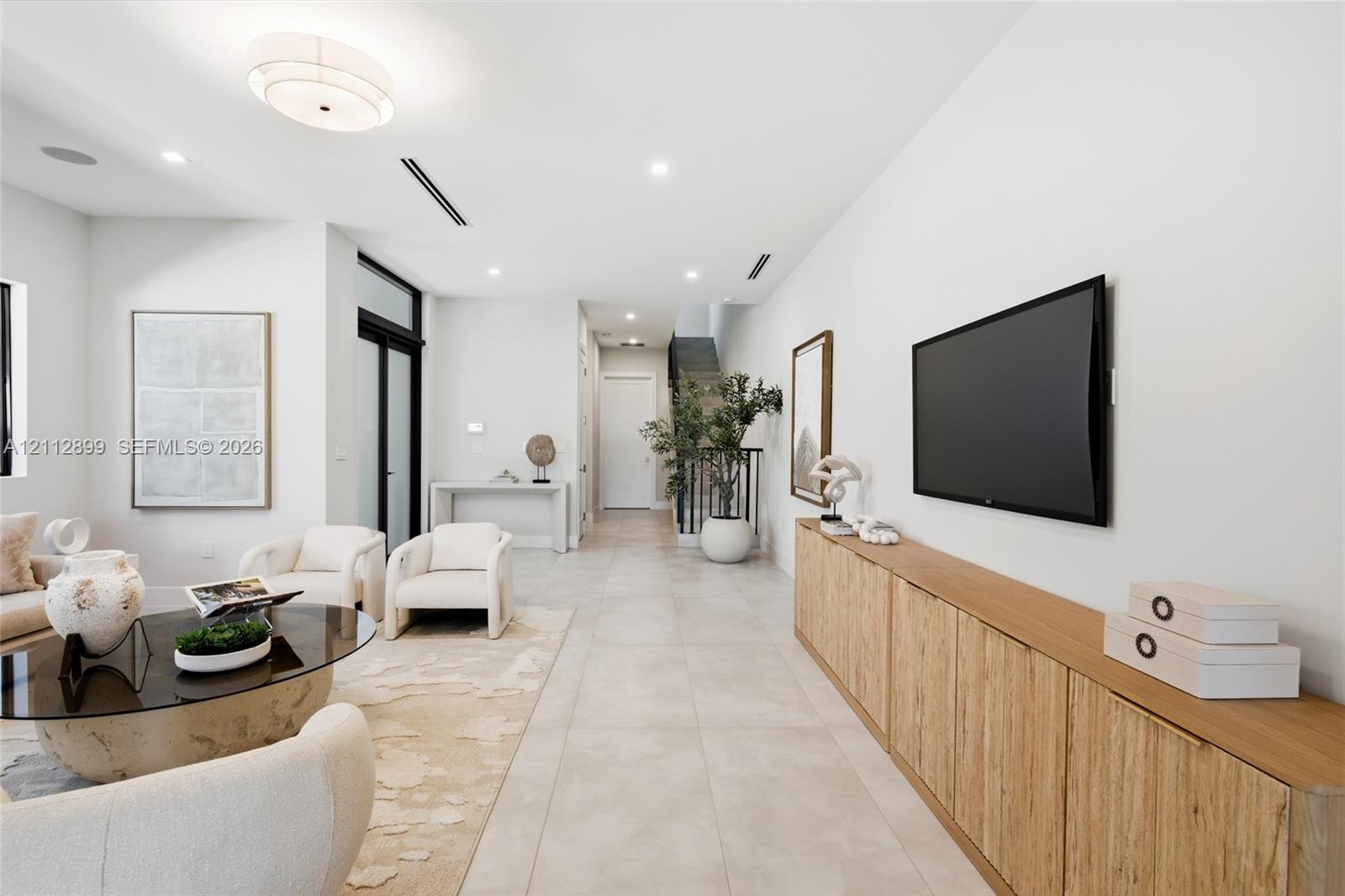 Large-format tile flooring, built-in wooden cabinetry, recessed lighting, and a multi-tiered drum light fixture