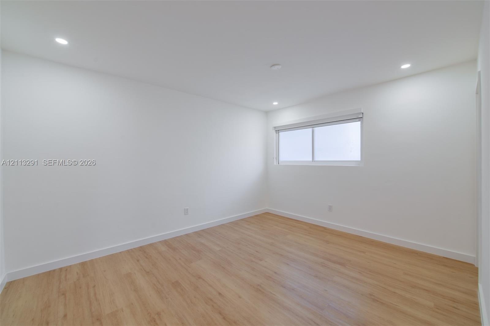 Interior space featuring wood-finish flooring, white walls, and recessed ceiling lighting