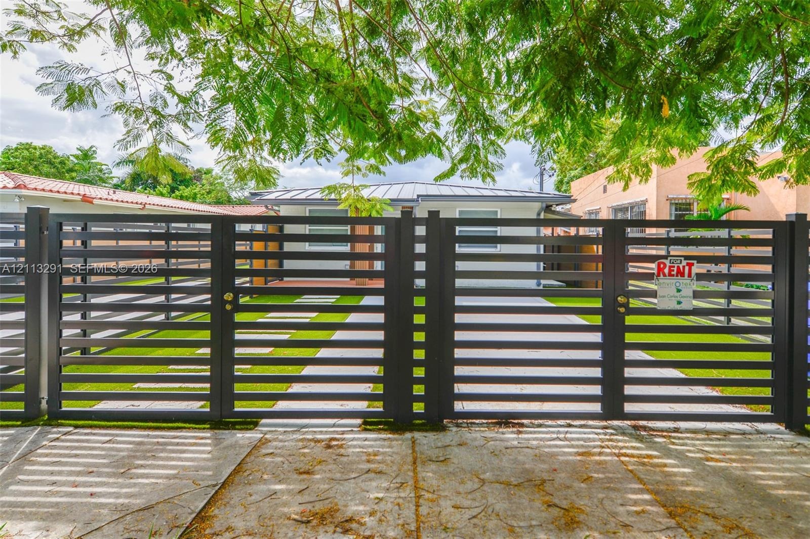 Horizontal slat metal entry gate with concrete paver walkway and synthetic turf lawn