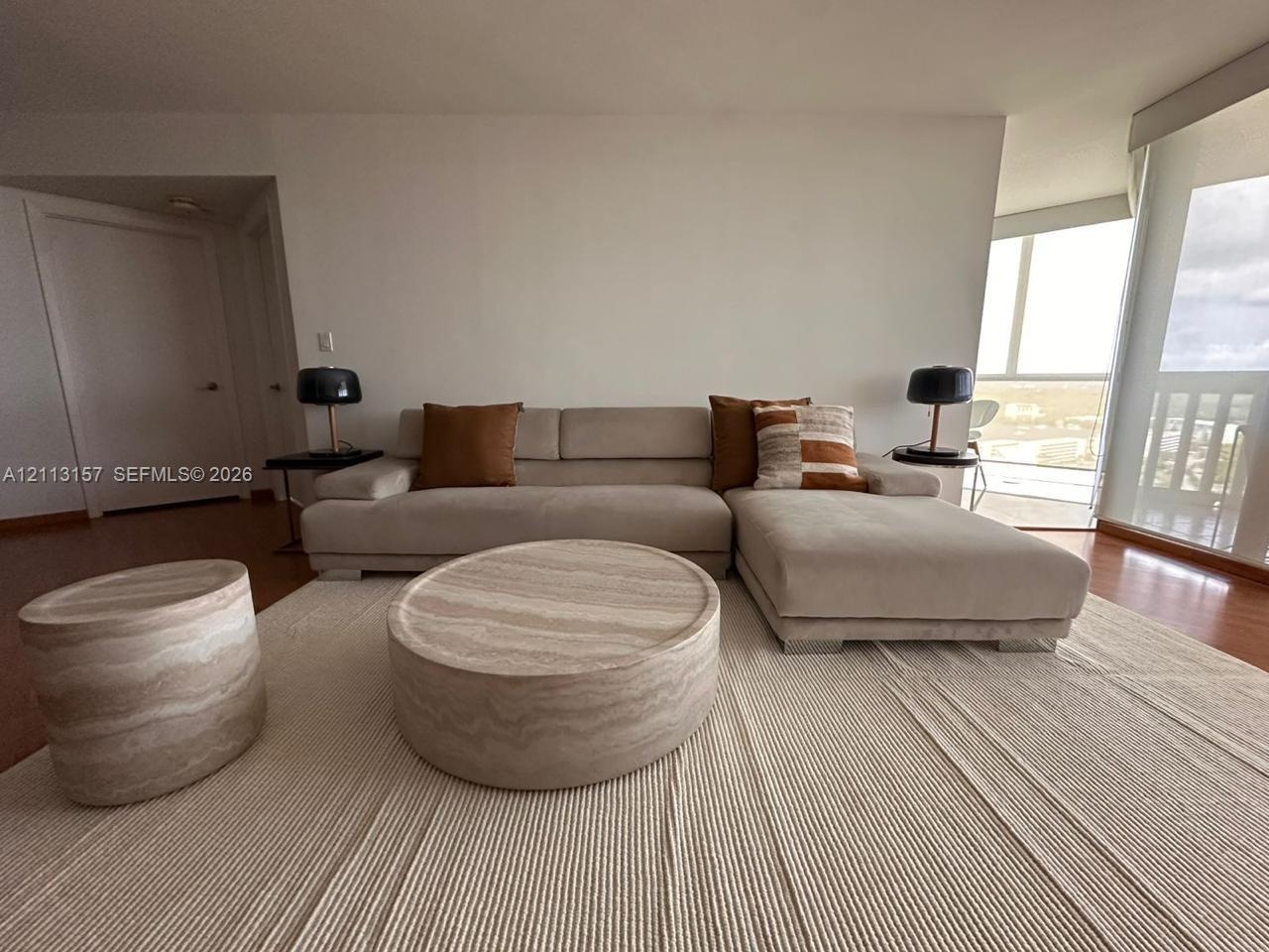 Living area featuring wood-finish flooring, floor-to-ceiling windows, and natural light exposure