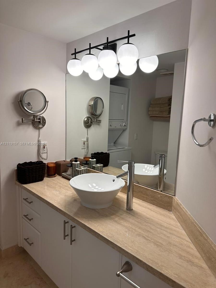 Vanity featuring a stone countertop, white cabinetry, vessel sink, polished chrome faucet, and multi-light globe fixture