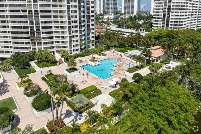 Outdoor swimming pool with integrated spa, paved terrace, and manicured landscaping featuring mature palm trees
