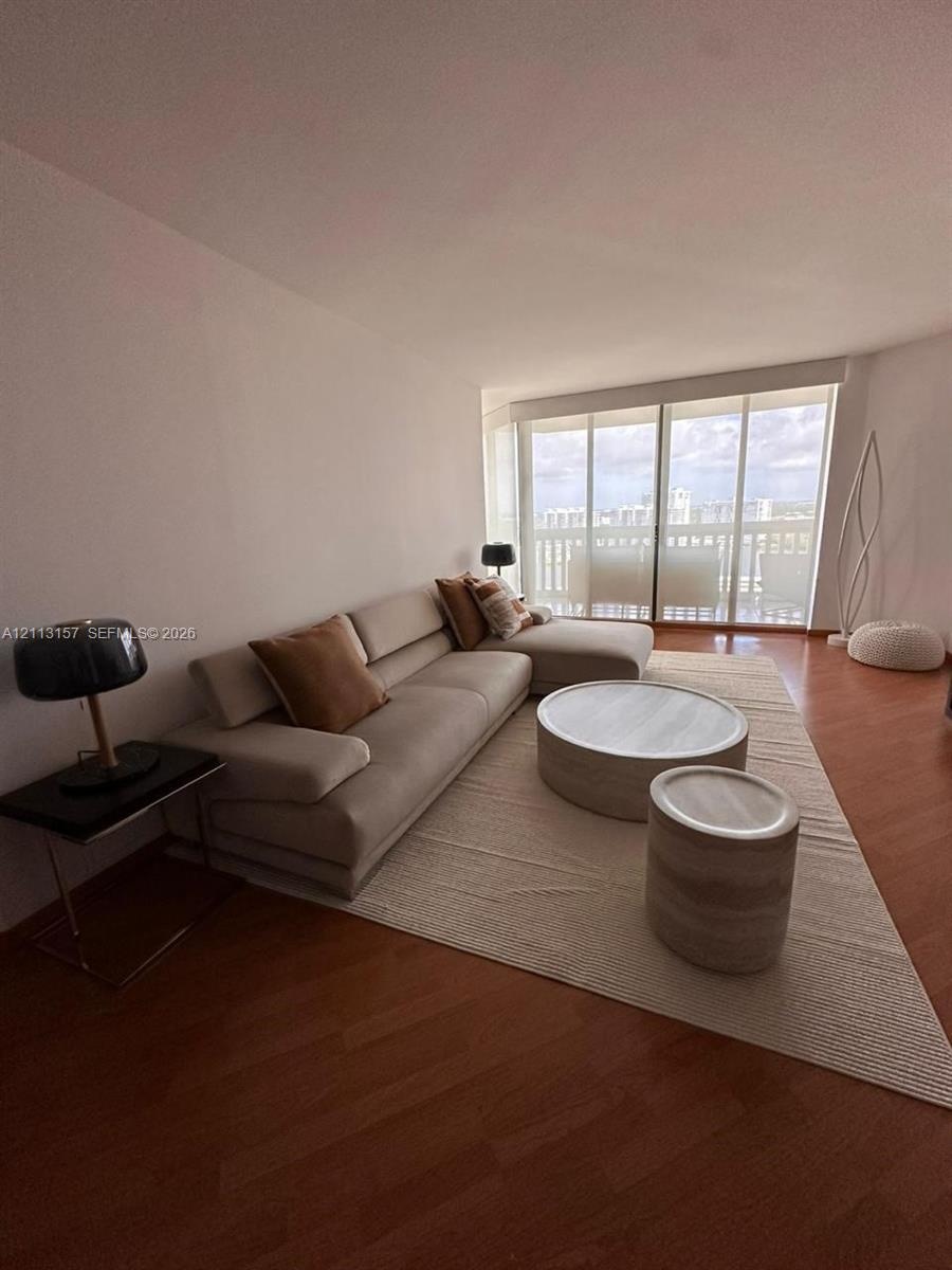 Living area featuring wood-finish flooring and expansive floor-to-ceiling glass sliding doors