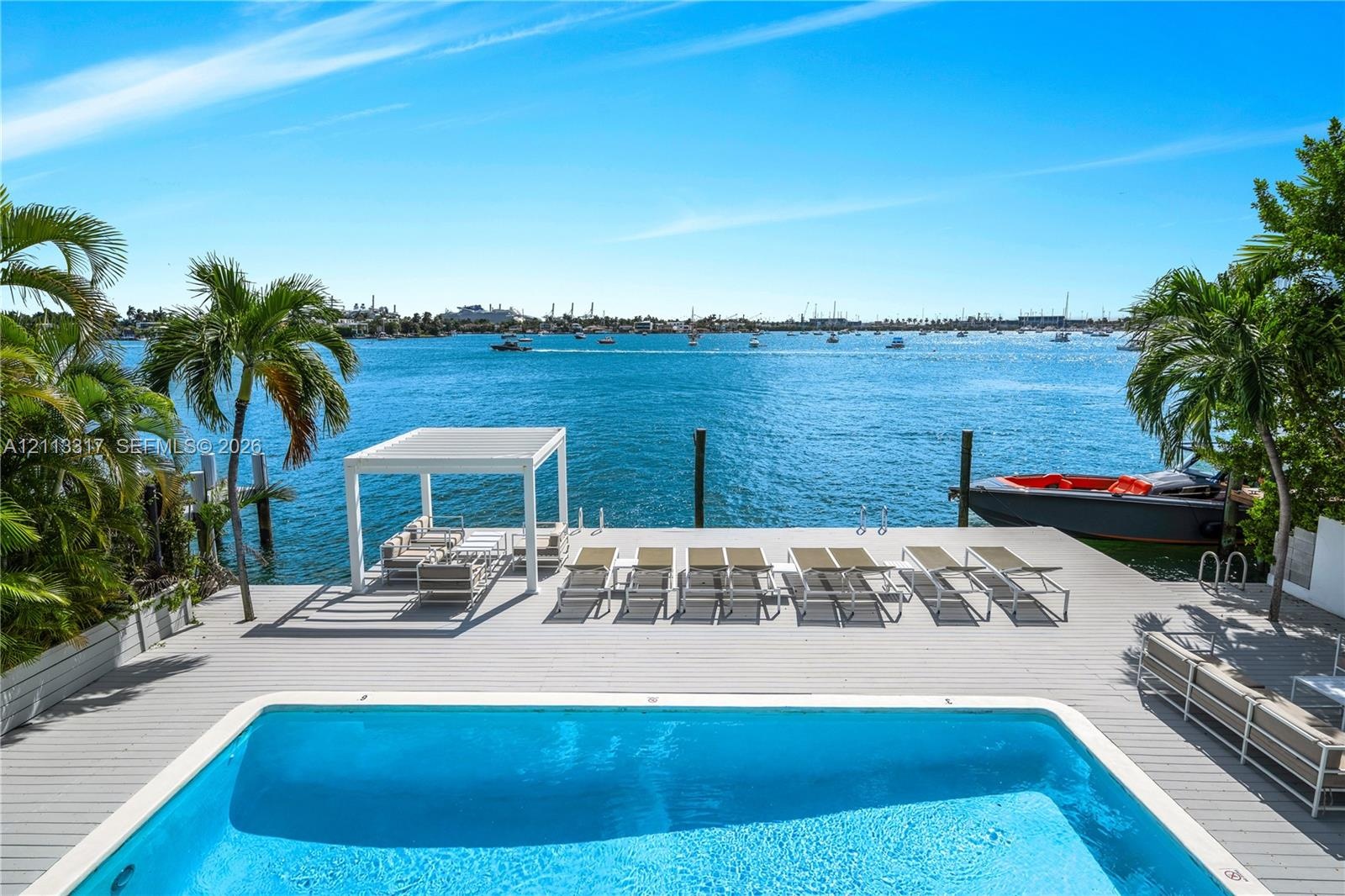 Waterfront deck featuring an inground swimming pool, a structural pergola, and a private dock