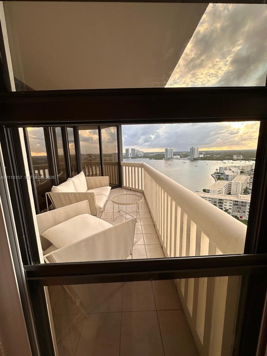 Private balcony featuring tile flooring, metal railings, floor-to-ceiling glass paneling, and water-fronting scenery