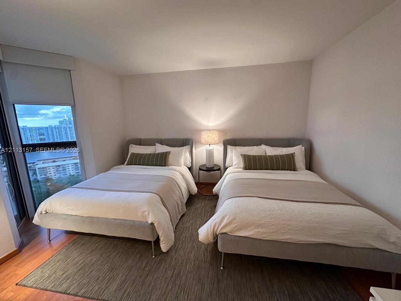 Wood-finish flooring, floor-to-ceiling window, and roller shade window treatment
