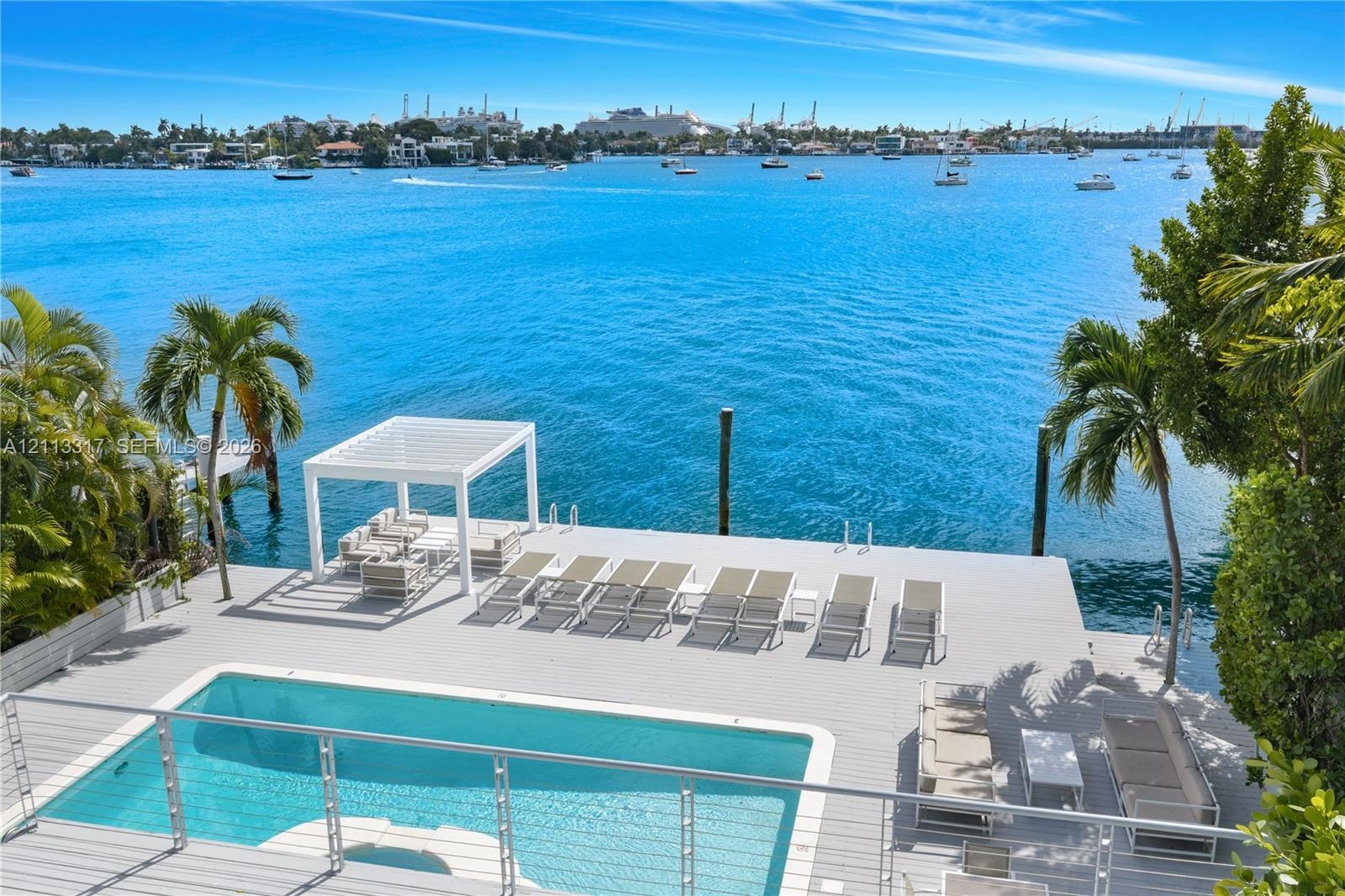 Waterfront terrace featuring a swimming pool, wood-finish decking, pergola, and cable railing system