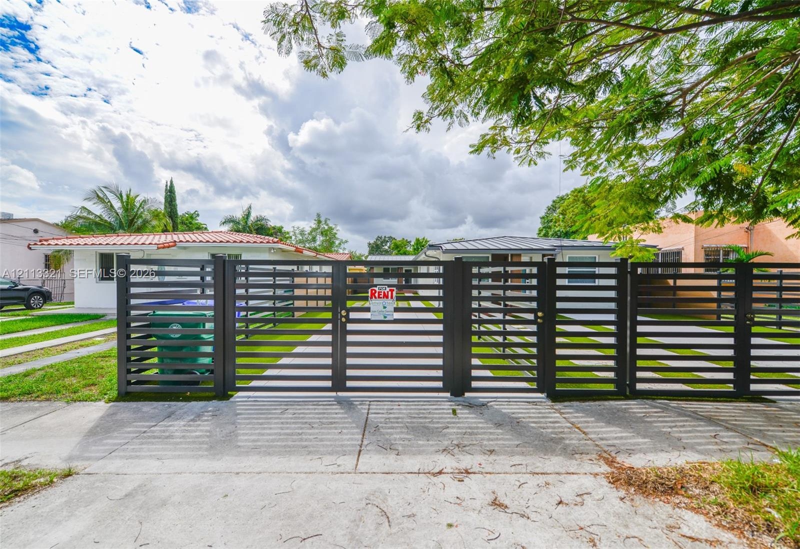 Horizontal slat metal gate, concrete driveway, and white exterior siding