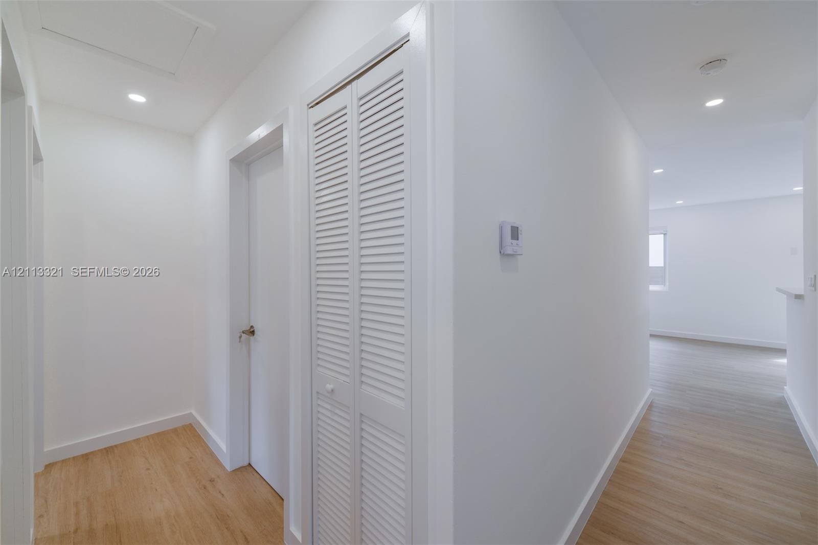 Hallway featuring wood-finish flooring, recessed lighting, and a white bi-fold closet door