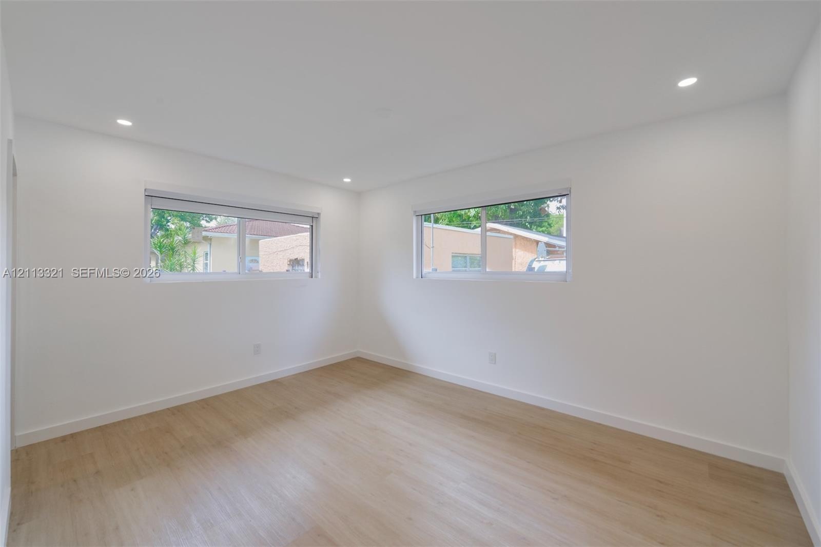 Bright interior room featuring wood-finish flooring, recessed lighting, and dual slider windows