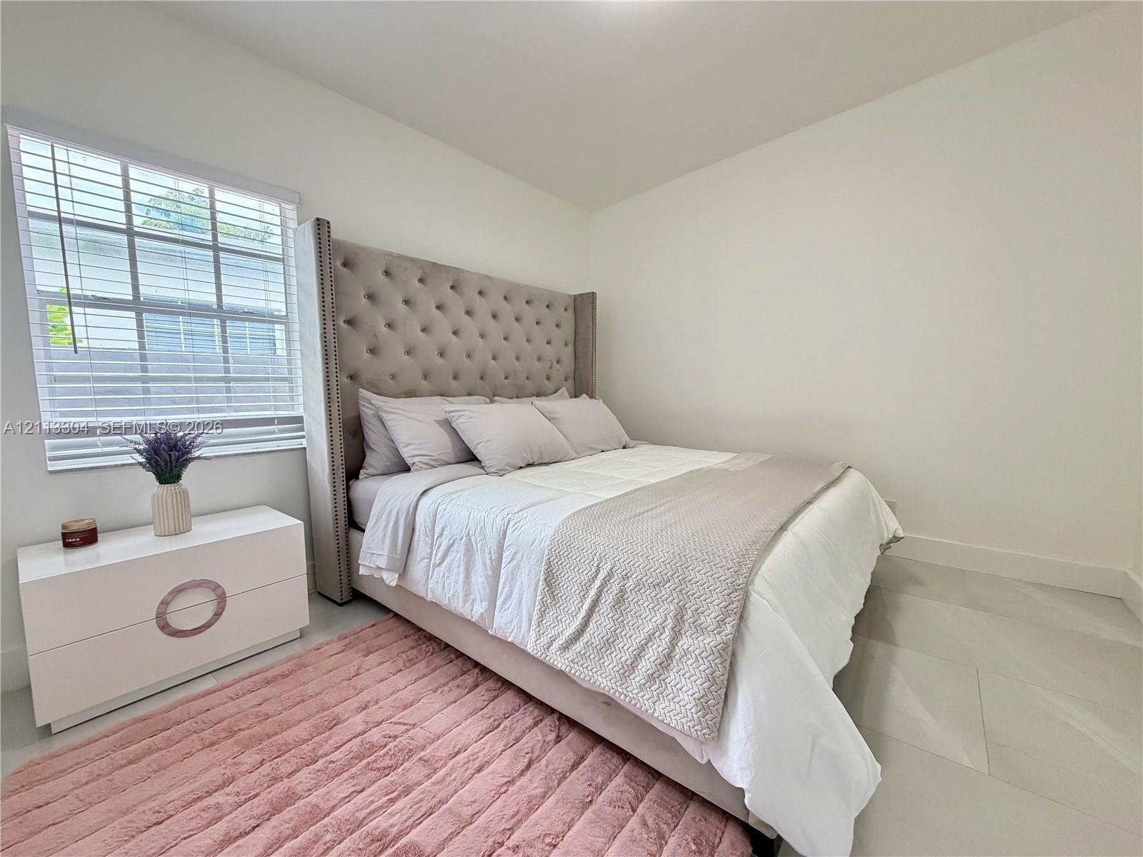 Neutral wall paint, light-toned large format tile flooring, and multi-pane window with white horizontal blinds