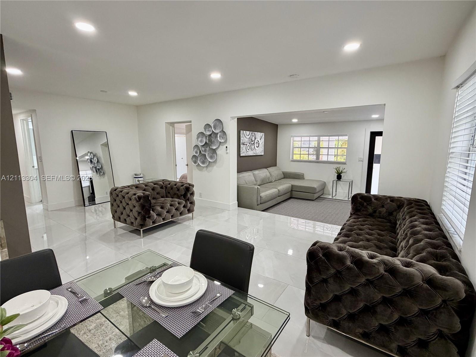 Open-concept interior featuring large-format polished tile flooring, recessed ceiling lighting, and a multi-pane window with white window blinds