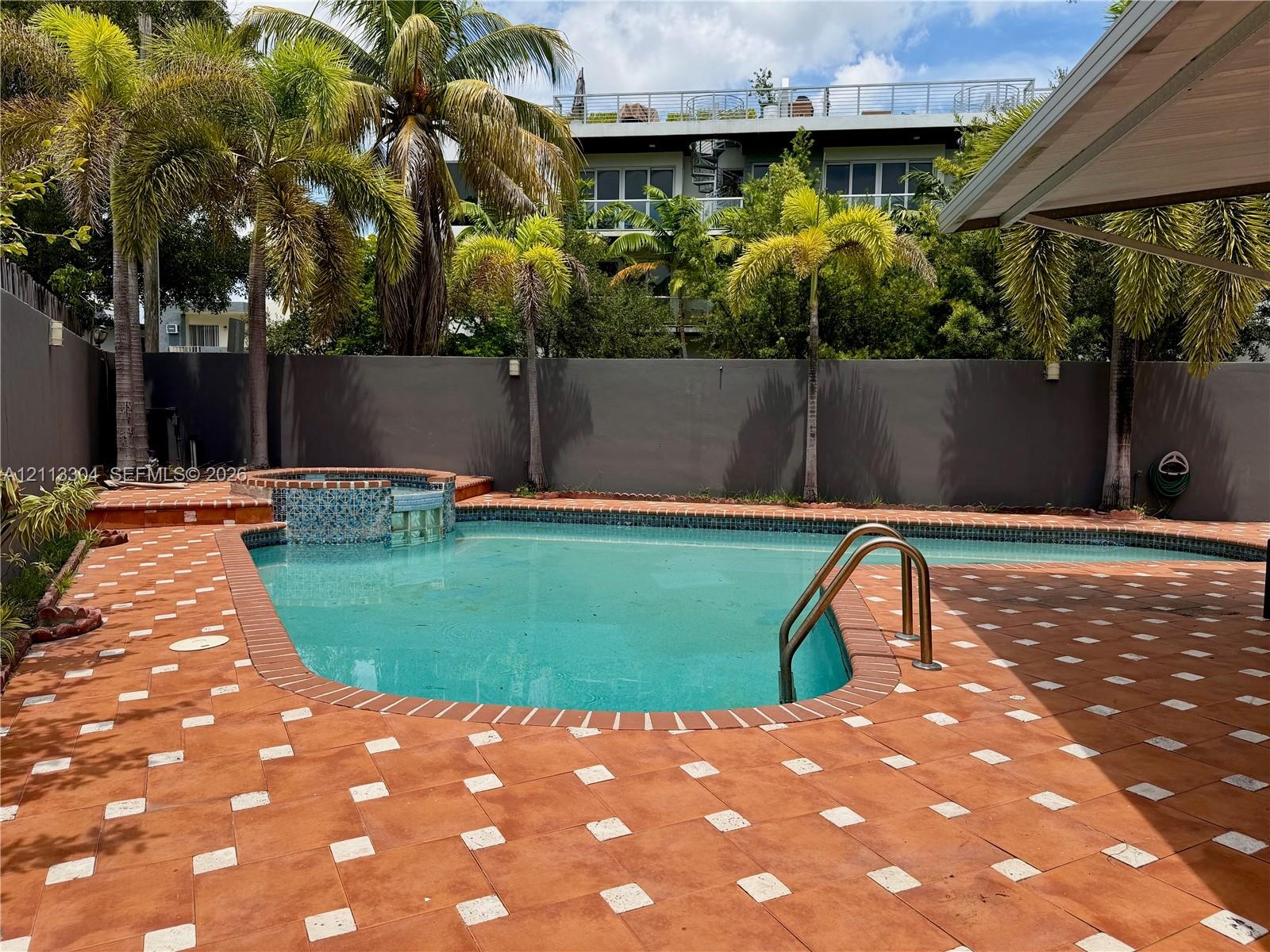 In-ground swimming pool with an integrated spa, mosaic tile detailing, and patterned paver surround