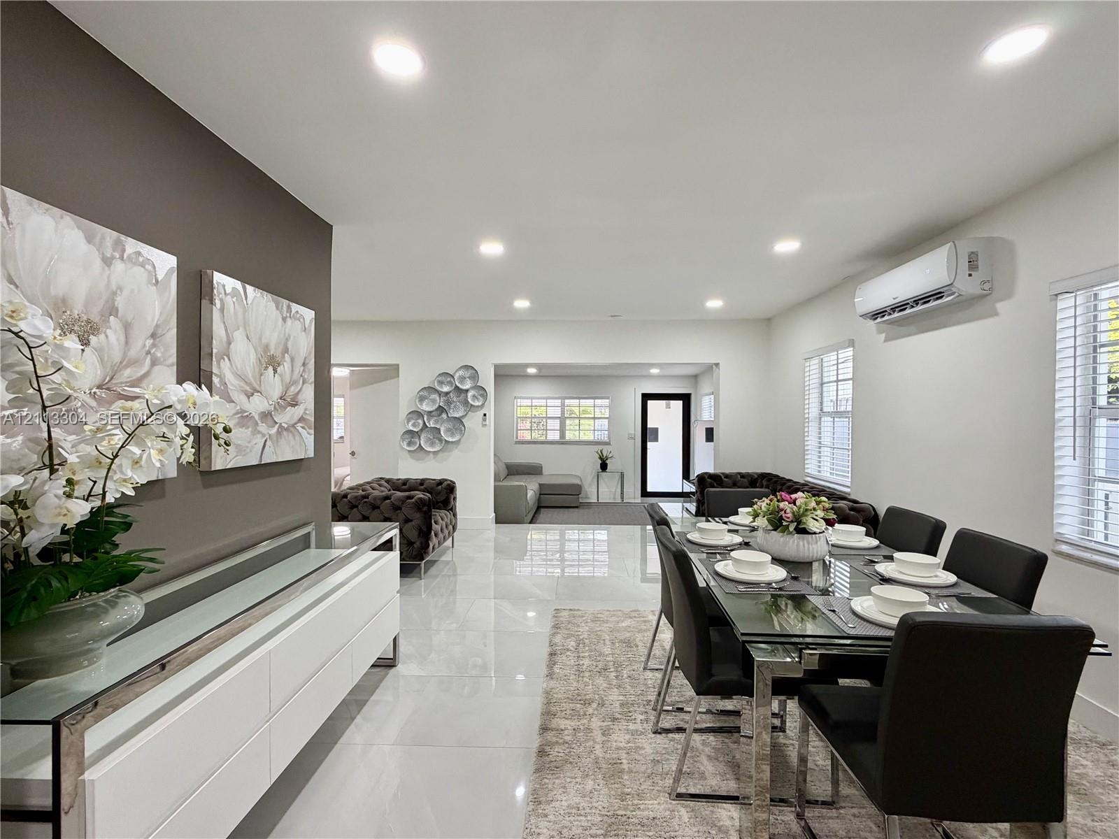 Open-concept space featuring polished tile flooring, recessed lighting, wall-mounted climate control unit, and crisp neutral wall tones