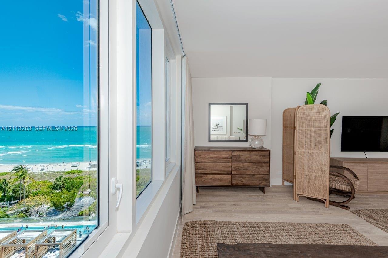 Floor-to-ceiling windows, light-toned wood-finish flooring, and ocean horizon backdrop