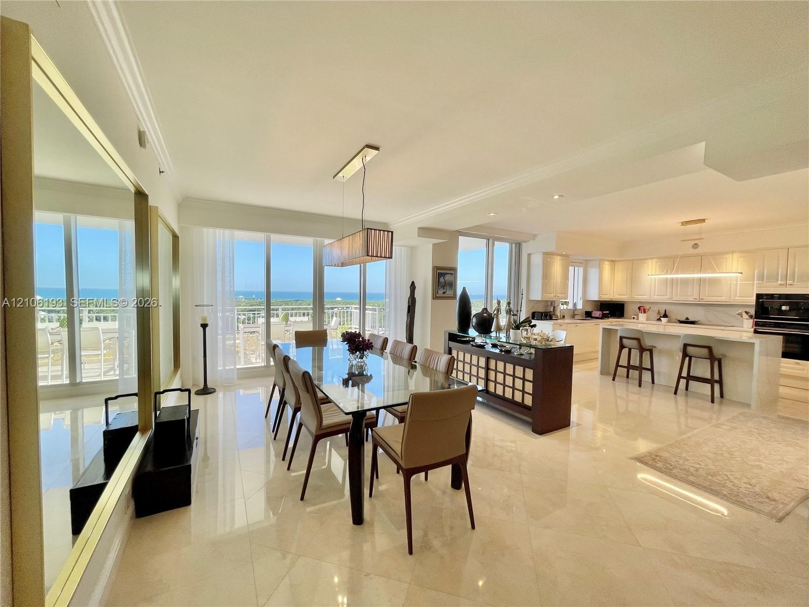 Open-concept living space featuring polished tile flooring, floor-to-ceiling glass sliding doors, custom white cabinetry, a built-in kitchen island wi