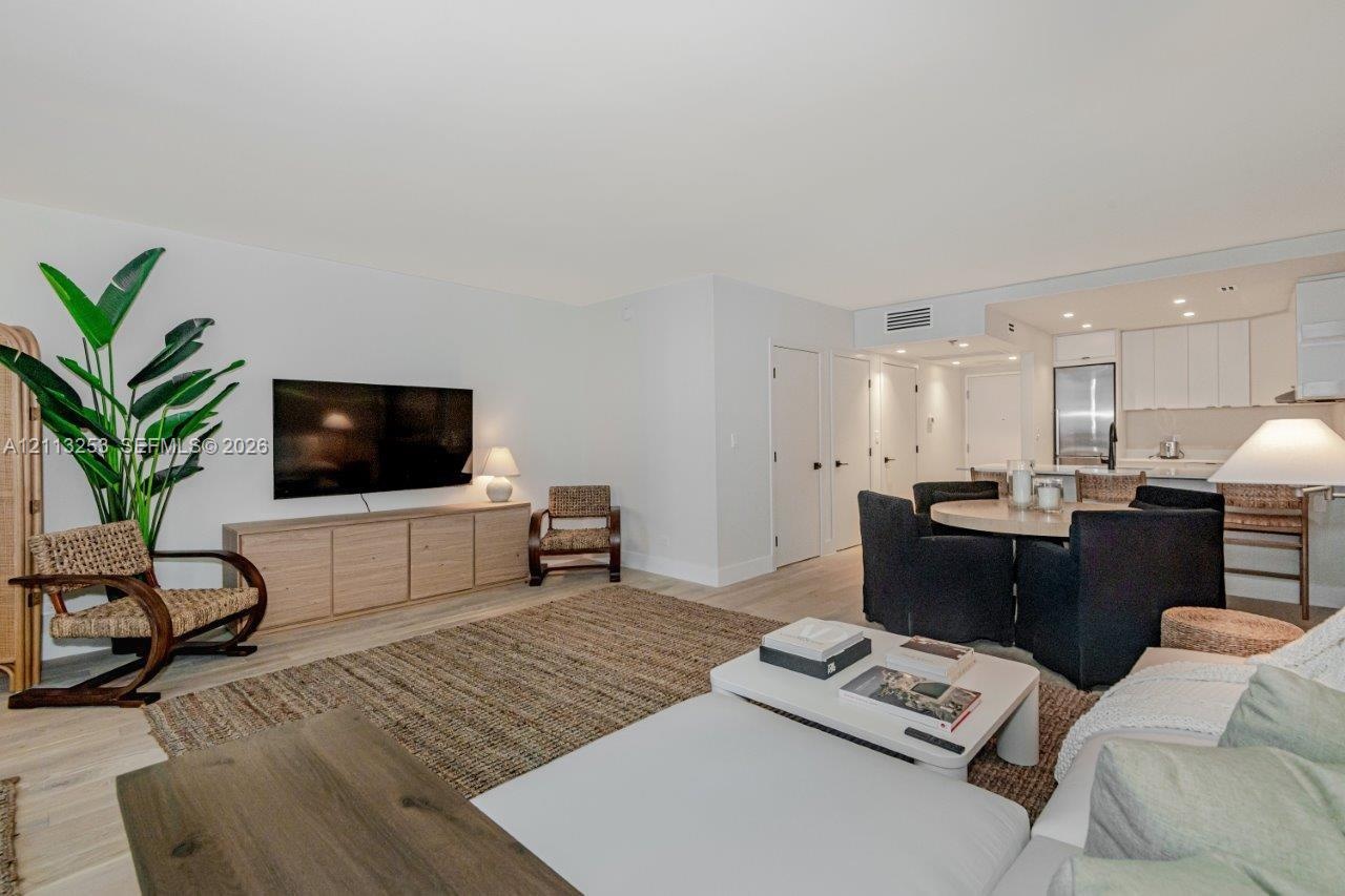 Open-concept floor plan featuring light-toned wood-finish flooring, recessed lighting, and kitchen cabinetry with integrated stainless steel appliance