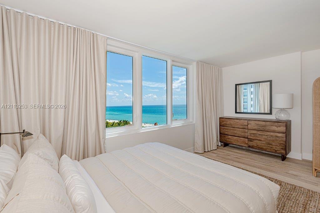 Expansive window wall with ocean and coastal horizon scenery, light-toned wood-finish flooring, and neutral wall palette