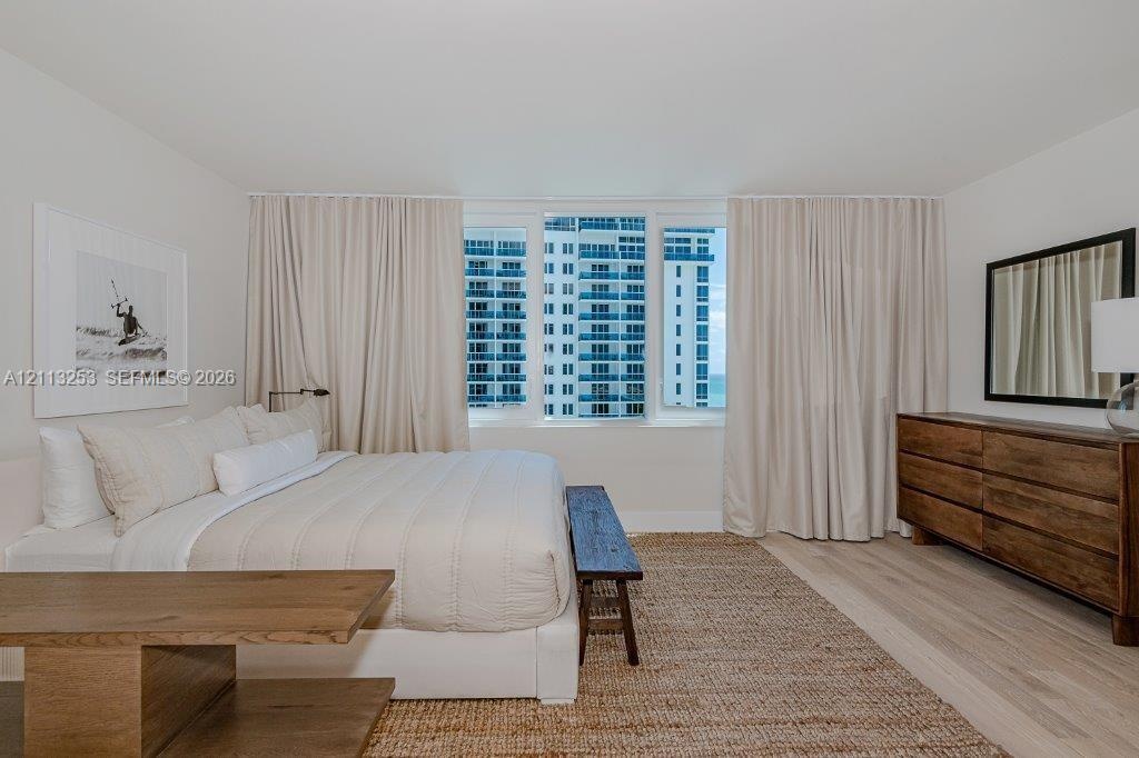 Floor-to-ceiling windows with neutral drapery and light-tone wood-finish flooring