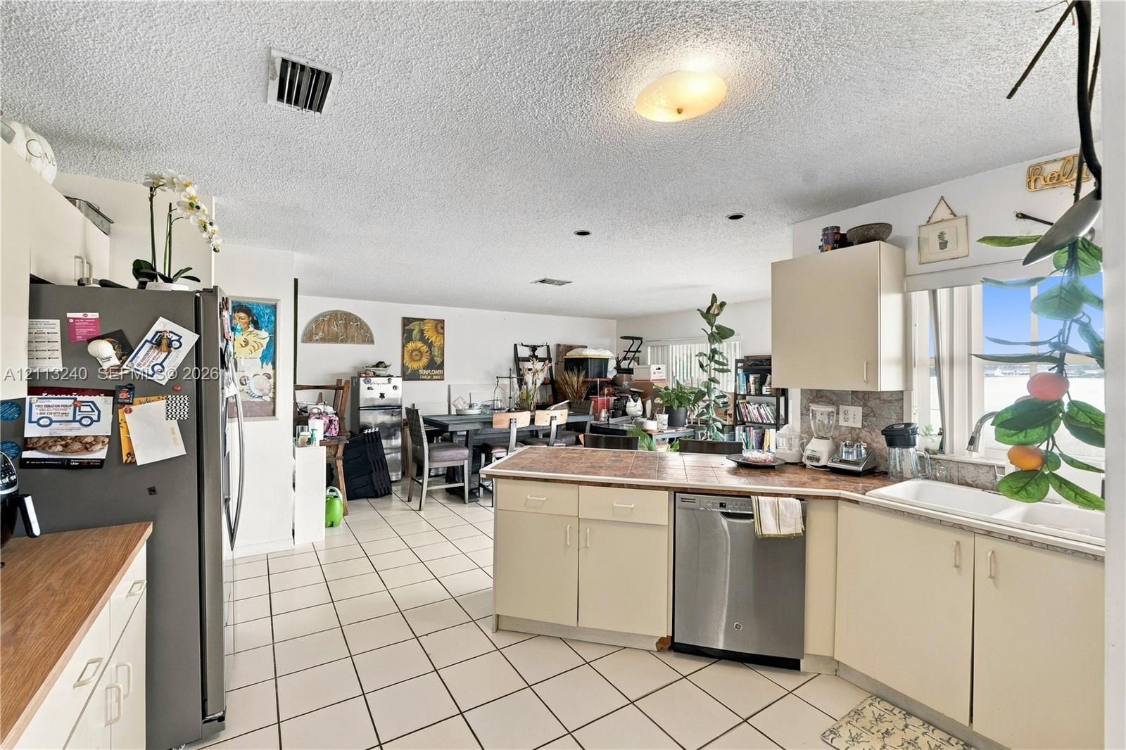 Kitchen featuring flat-panel cabinetry, tiled countertops, stainless steel dishwasher, double-basin sink, and tile flooring