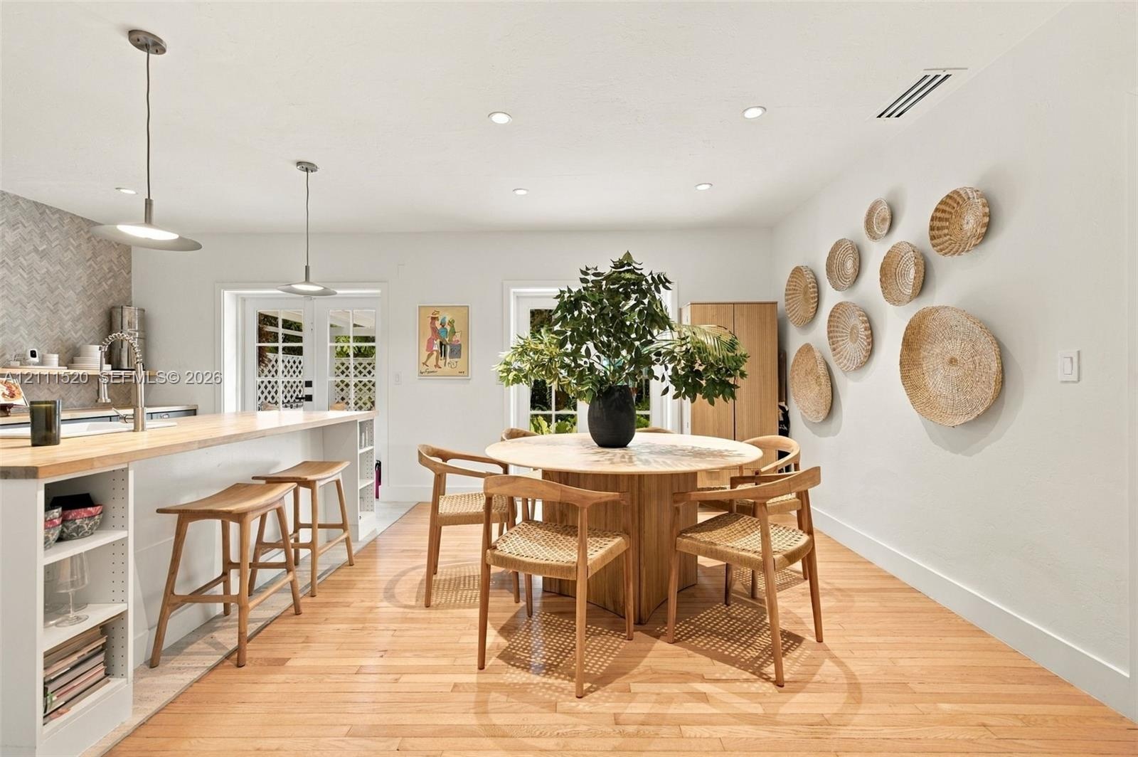 Kitchen featuring wood-finish flooring, a breakfast bar with wood countertop, recessed lighting, pendant fixtures, and a herringbone-patterned backspl