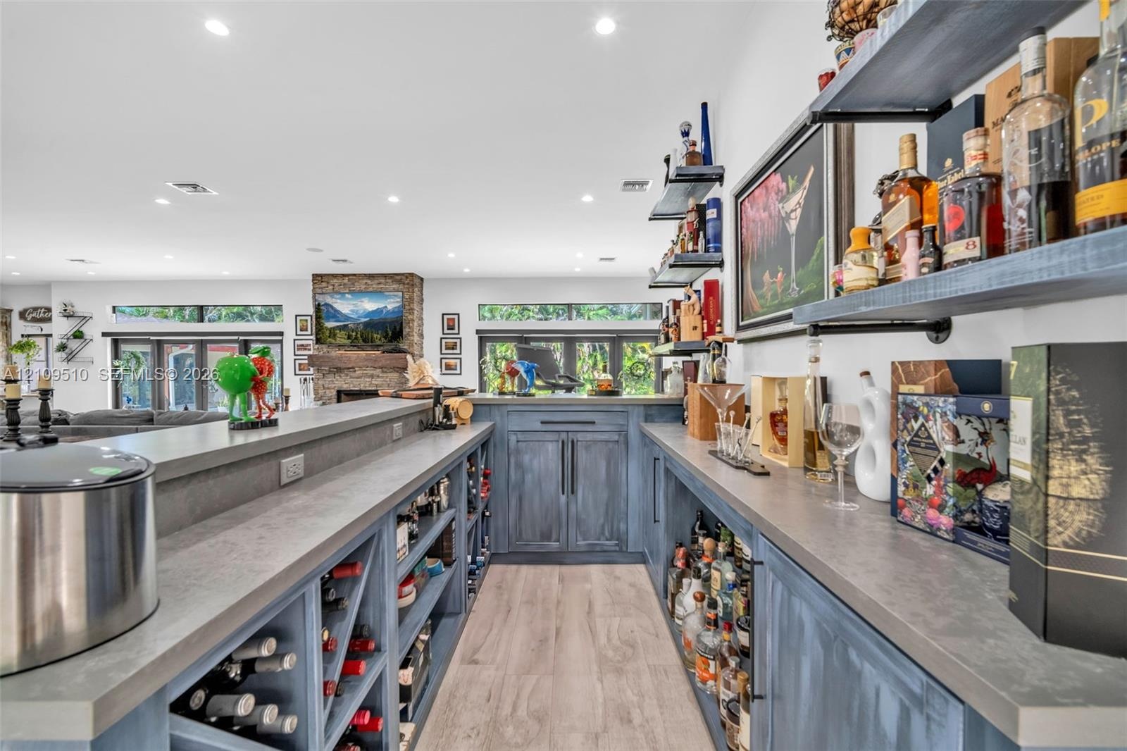 Custom built-in bar featuring stained wood cabinetry, stone countertops, integrated wine storage, and floating wall-mounted shelving with recessed lig