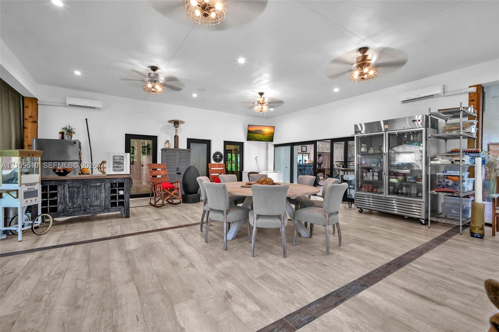 Open-concept area featuring wood-finish flooring, recessed lighting, multiple ceiling fans, and two wall-mounted ductless climate control units