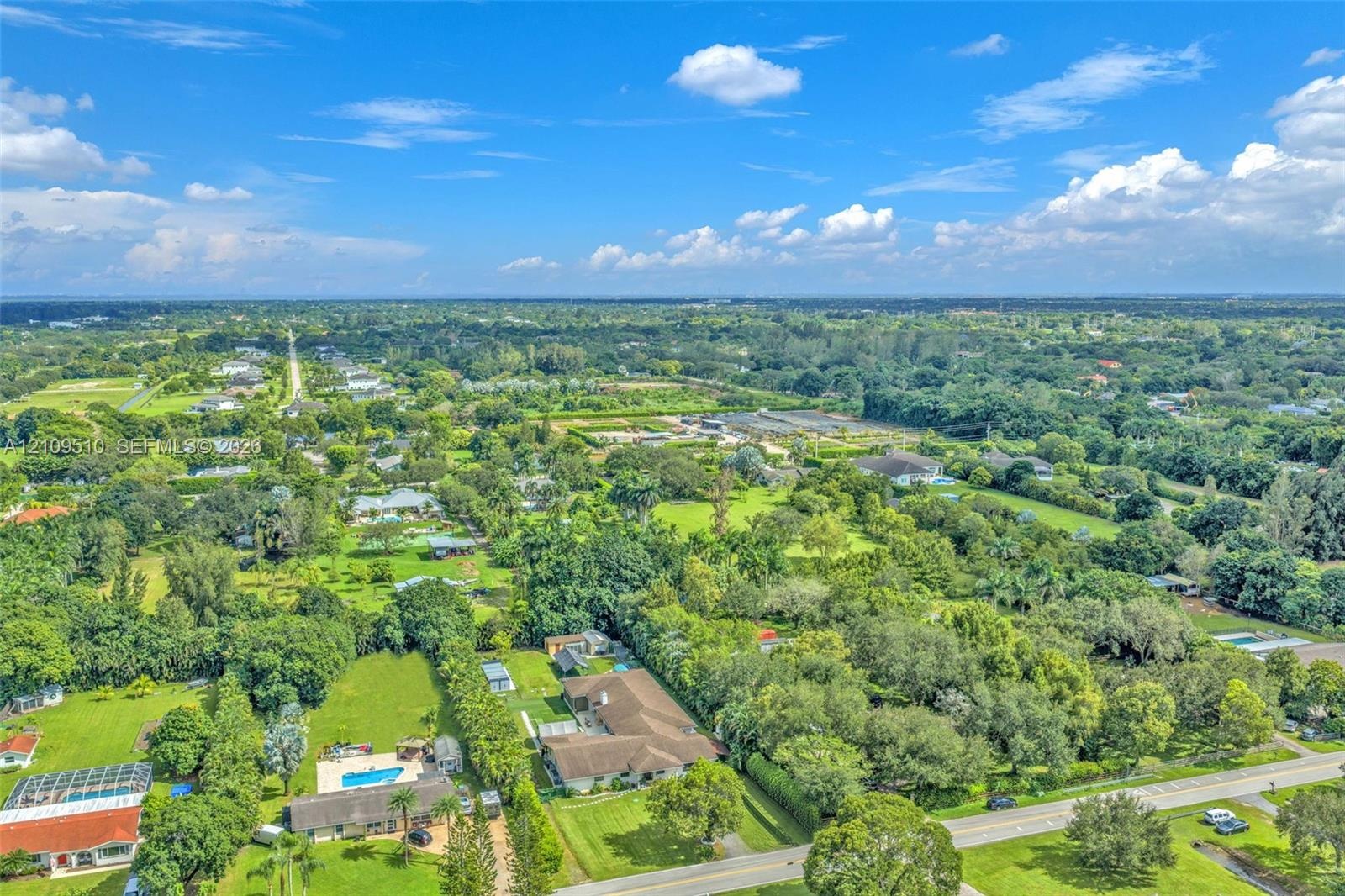 Aerial perspective of a sprawling residential property featuring a multi-gable roofline, a private in-ground swimming pool, extensive lawn space, and 